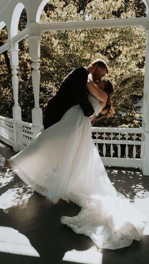 Flowing white wedding dress twirling on a white gazebo porch with sunlight casting dramatic shadows.