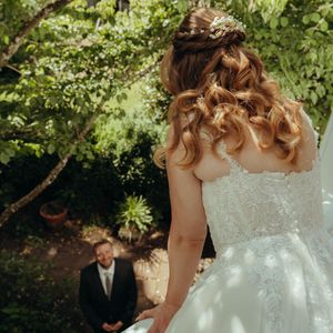 A couple in wedding attire shares a romantic moment together in a lush garden setting during their celebration.