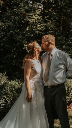 A couple shares romantic moments in an outdoor garden setting on their wedding day.