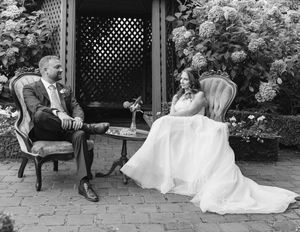 Black and white photograph of a couple sharing a moment on a garden patio with lattice backdrop.
