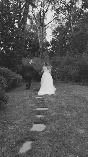 A black and white photo of a couple walking along stepping stones through a garden path.