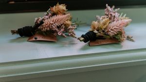Delicate pink dried flowers and foliage arranged in a row on a light surface.