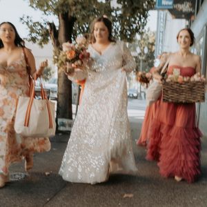 Wedding party in flowing dresses of blush pink and terracotta colors pose together outdoors.