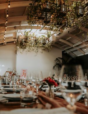 Elegant wedding reception table settings with hanging greenery and soft lighting.