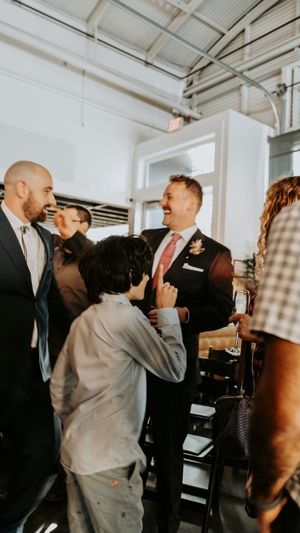 Wedding guests mingling and socializing in a bright industrial-style venue space.