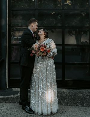 Intimate wedding moment captured outside against dark windows at dusk.