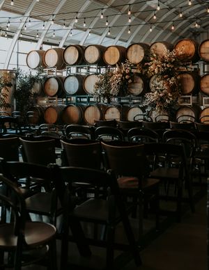 Interior of a winery event space with rustic wooden barrels and tables set for a celebration.