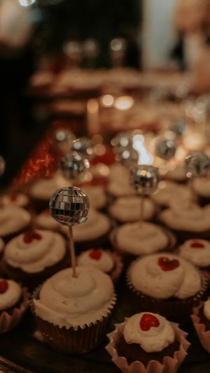 Wedding cupcakes decorated with white frosting and small red heart details on display.