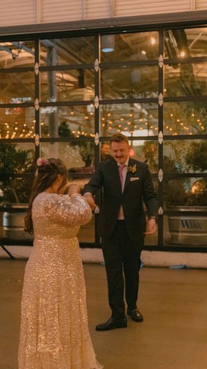 A couple shares a romantic moment under warm lighting in an industrial-style wedding venue.