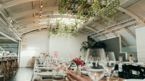 Modern event venue interior with white beams and hanging greenery decorations.