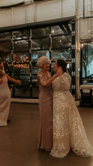 A tender dance moment at a wedding reception under ambient string lights.