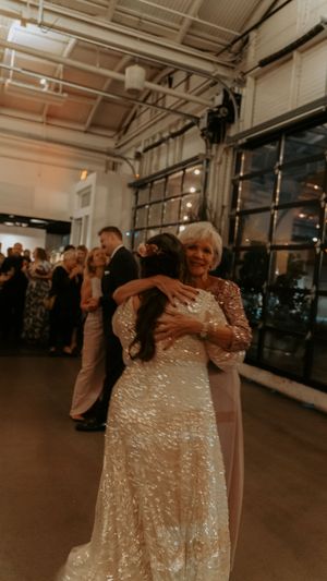 A couple dances together at an indoor venue with sparkling sequined dress and romantic lighting.