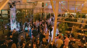 Crowded restaurant interior with warm lighting showing multiple dining tables and guests during peak dinner service.