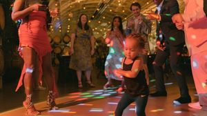 People dancing on a colorful illuminated dance floor with disco lights creating a festive party atmosphere.