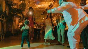 Party guests dancing under ambient lighting with palm trees and decorative elements creating a tropical vibe.