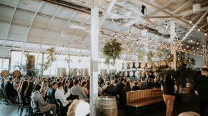 Panoramic view of a wedding reception space with twinkling lights and white ceiling beams.