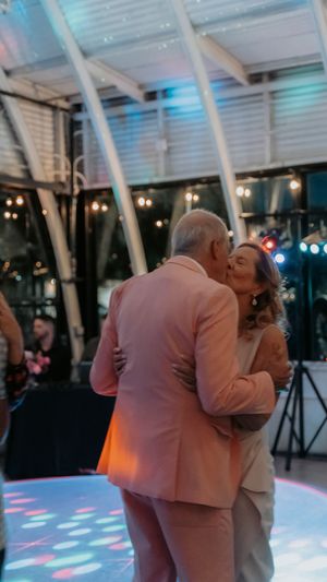 Couple sharing an intimate dance moment on an illuminated dance floor with colorful lighting effects.