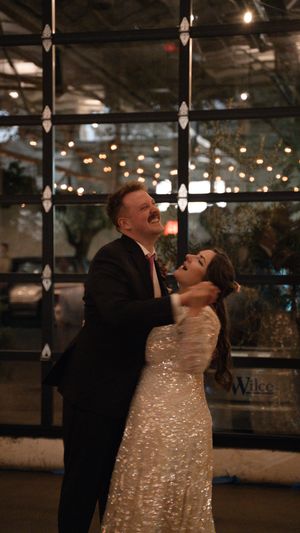 A romantic dance moment in a venue with sparkling lights and a glittering sequined dress.