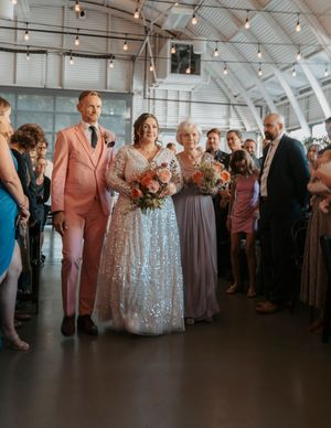 Wedding party gathers in a modern industrial venue with string lights overhead.