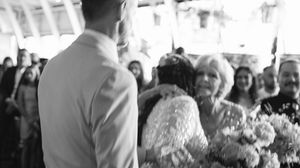 A wedding ceremony moment captured in black and white with guests looking on as a couple exchanges vows.