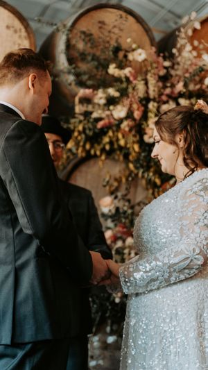 Romantic wedding moment captured with floral backdrop and sparkly dress details.