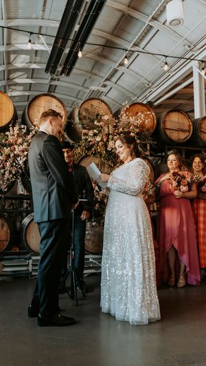 Wedding celebration in an industrial venue with wine barrels and romantic lighting.