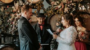 Wedding ceremony in a rustic venue with floral arch decorations and romantic lighting.