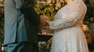 Close-up of an elegant sparkly wedding dress with floral decorations in warm lighting.