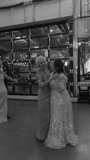 A couple dances together at an indoor venue, with the woman wearing a sparkly evening gown.