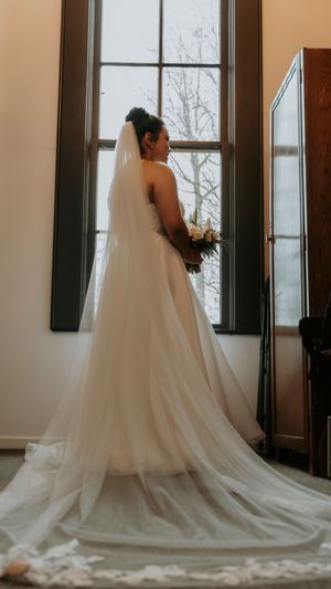 A flowing white wedding dress with a long train captured in sequence against a bright window backdrop.