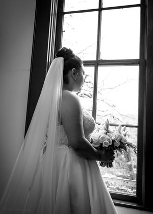 A series of black and white photos showing a bride in a flowing white gown gazing out of windows in contemplative poses.