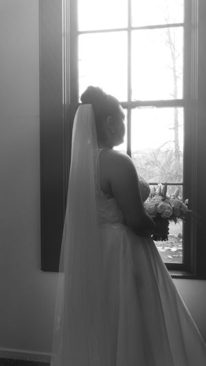 A series of black and white silhouettes showing a bride in a flowing white dress gazing out windows.