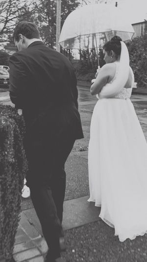 A series of black and white photos showing a bride and groom walking together outdoors in formal wedding attire.