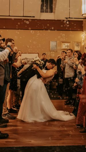 Wedding guests blow bubbles during a reception celebration as a couple dances.