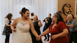 Wedding reception guests dancing and celebrating together in a bright indoor venue.