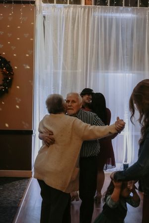 People embrace in a group hug during an emotional moment at an indoor event.
