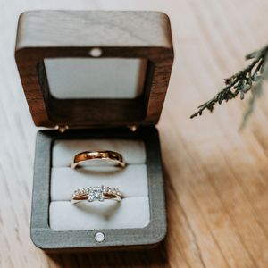 A series of close-up shots showing engagement rings in gray jewelry boxes displayed on a wooden surface.