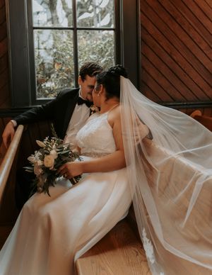 A flowing white wedding dress and veil captured in a series of artistic detail shots against a dark wood background.