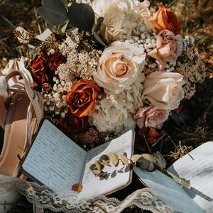Wedding details featuring delicate handwritten vows alongside peach and burgundy roses with white floral arrangements.