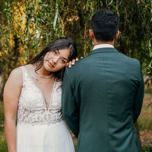 A couple in wedding attire stands together in a lush garden setting during an intimate outdoor photo session.