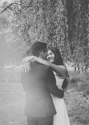 A couple embraces in a tender moment during their wedding photoshoot in a misty forest setting.