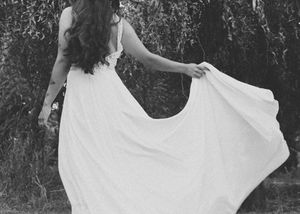 A bride in a flowing white dress twirls joyfully in a series of black and white photos outdoors.