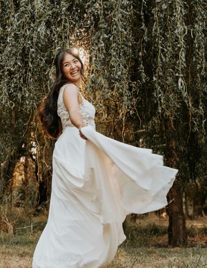 A flowing white dress twirls gracefully in a forest setting during golden hour sunlight.