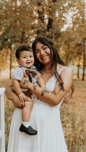 A joyful moment captured outdoors with a white dress and autumn trees in the background.