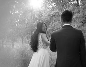 A couple in wedding attire walks together through a misty forest setting creating a dreamy romantic atmosphere.