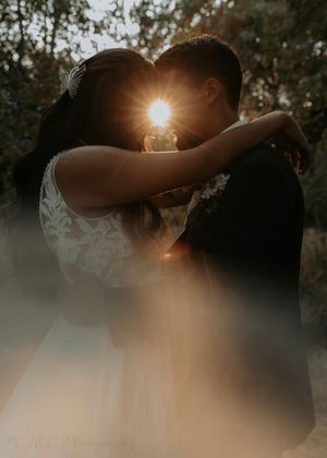 Dreamy silhouettes in white against sunlit forest backdrop create magical wedding photography moments.