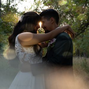A romantic wedding portrait with soft focus and natural lighting in a wooded setting.