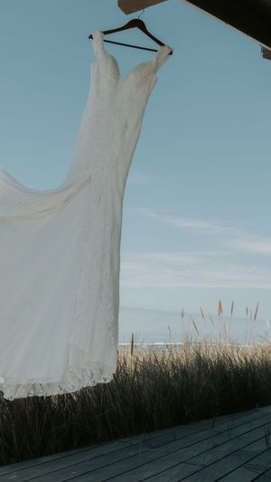 White dress blowing in the wind on a clothesline against a blue sky and tall grass landscape.