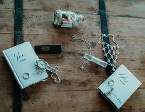 Handwritten wedding vows on white paper with decorative rings and ribbons on rustic wooden surface.