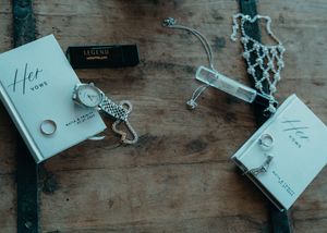 A rustic wooden table surface with scattered white gift tags and decorative keys arranged in a flat lay composition.